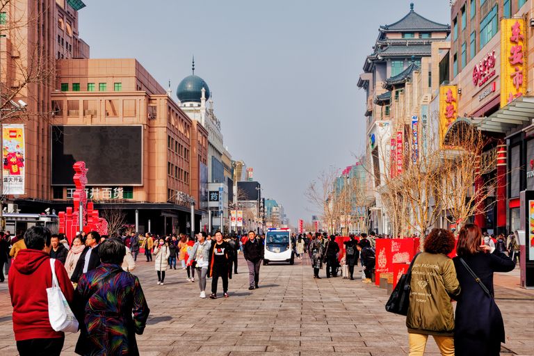 Busy pedestrian street in Beijing, China, bustling with people under clear skies.