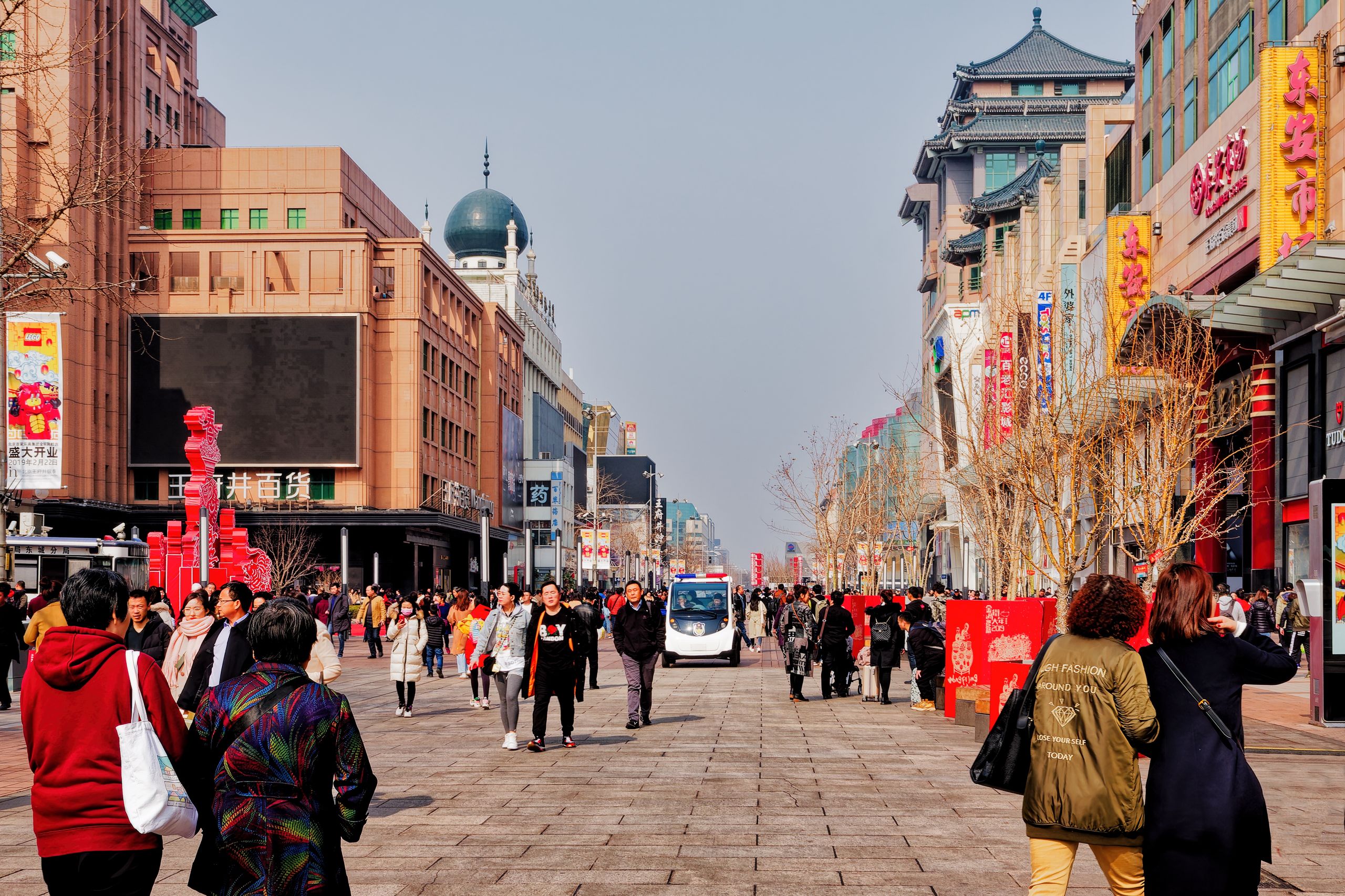 Busy pedestrian street in Beijing, China, bustling with people under clear skies.